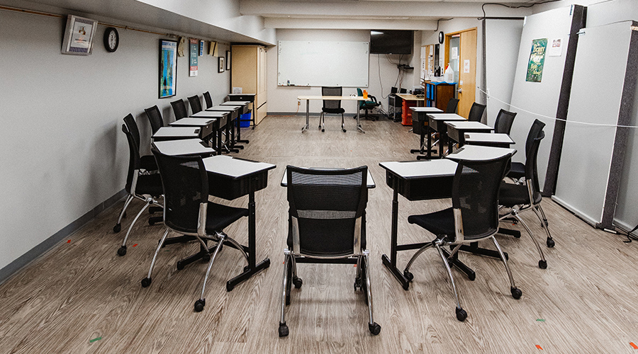 classroom with desks arranged in a circle, the instructors desk is part of the group