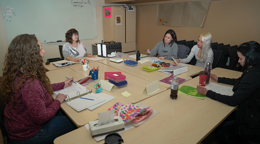 group of participants sitting around a table taking notes as facilitator speaks