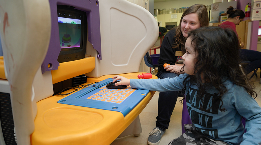 child using children's computer workstation with adult nearby