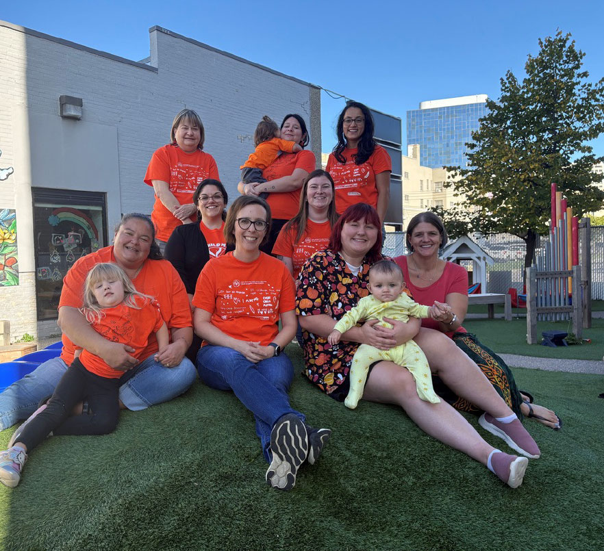 team photo where everyone is wearing matching orange t-shirts